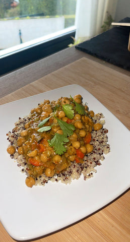 Plate of chickpea vegetable curry served on a bed of quinoa topped with coriander
