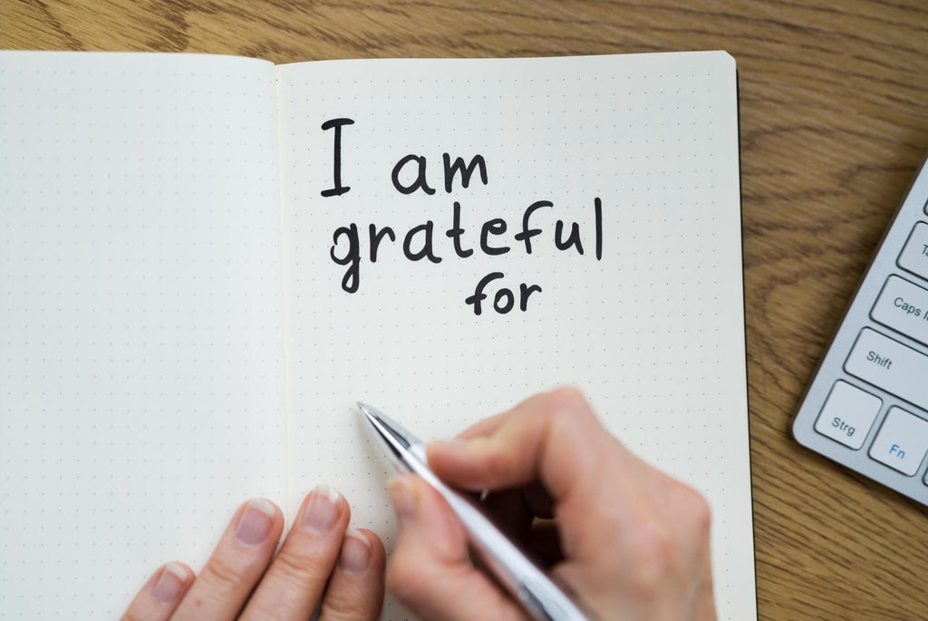 A person writing in journal what they are grateful for. 