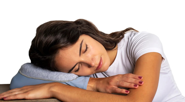 Young woman resting her head on a Sleepy Sleeve travel pillow.