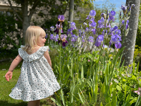 girl in twirly dress in front of blue iris flowers