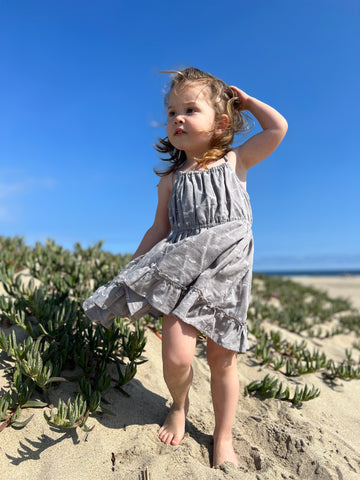 girl on windy beach wearing grey whale dress