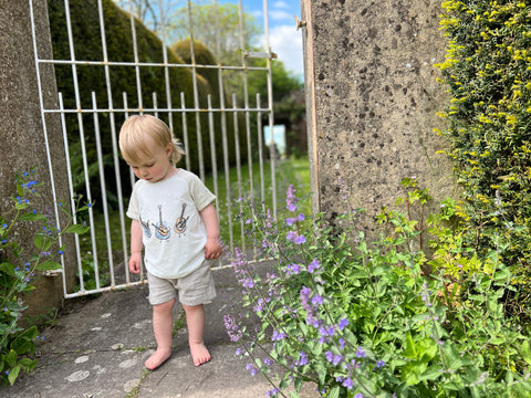 toddler in front of old iron gate wearing guitar tee shirt and grey shorts
