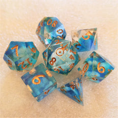 A set of dice that are part clear and part translucent light blue. They have clouds of white in them and gold numbers.