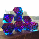 A set of translucent dice backlit by a window behind them. They are half vibrant blue and half bright pink and contain flecks of copper foil in them.
