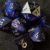 A close up image of a set of dark dice. They have a pink and blue shimmer that runs through the center of each die.