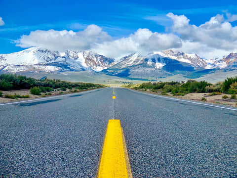 A road with snow capped Sierra Nevada mountains in the background Lee Vining, California