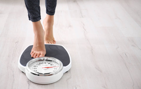 image of woman from the calves down, stepping on a scale