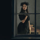 Woman in Victorian Clothing looking out a window