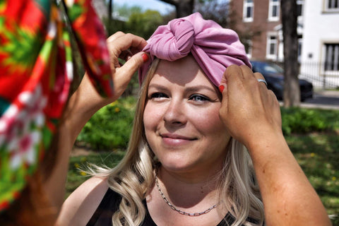 Femme rayonnante se fait replacer un bonnet rose et une prothèse capillaire blonde cheveux longs.
