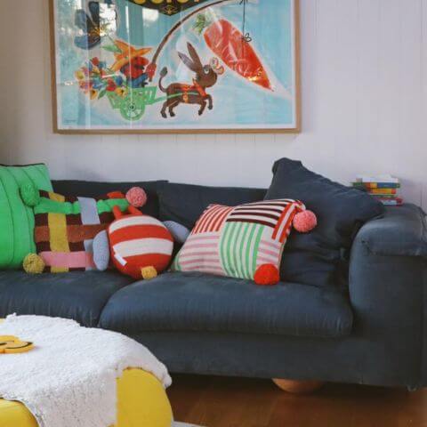 Vintage retro lounge room with navy sofa and mixed colourful patterned cushions on sofa