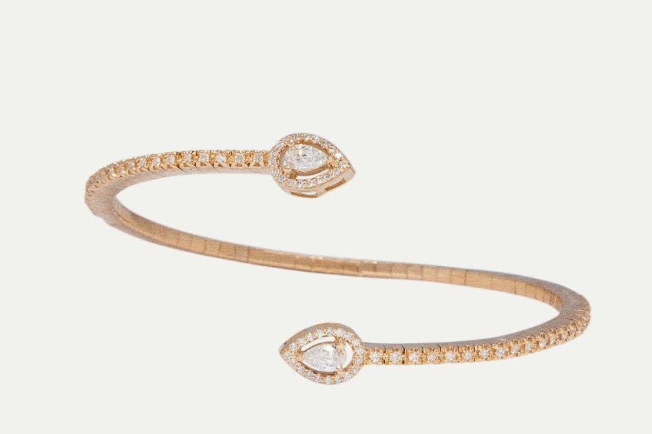 The Eyelette Bangle is made with 18K rose gold, 77 round diamonds and 2 pear cut diamonds. This stunning piece is a reimagined wraparound bangle that fits elegantly around the wrist