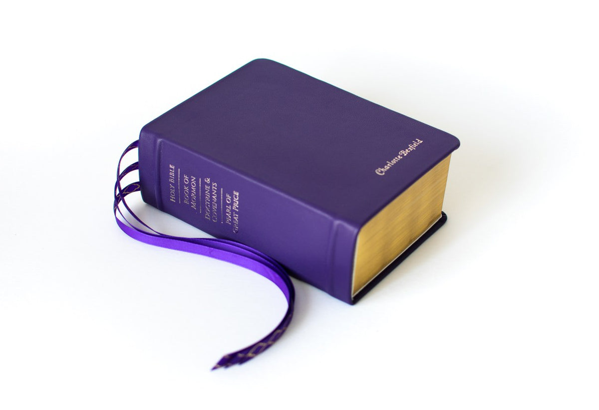 Amethyst Leather Quad Engraved with Gold Lettering and Ribbon Bookmarks, in Front of a White Background - Custom LDS Scriptures & Rebinding Services