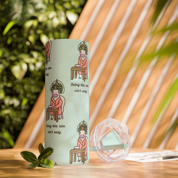 tumbler with a lid and straw placed on a table with leaves around