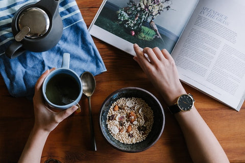 Person Holding Blue Ceramic Mug and White Magazine