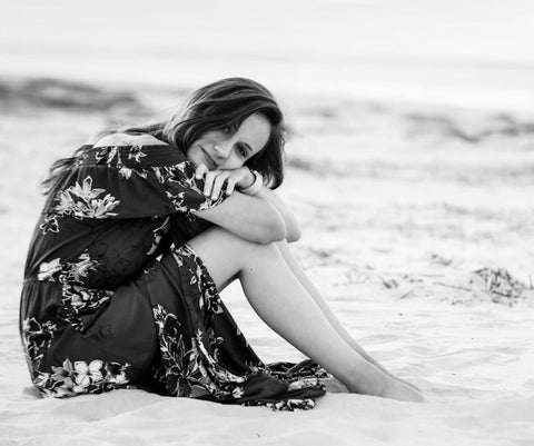 Woman In Black And White Floral Dress Sitting On The Beach