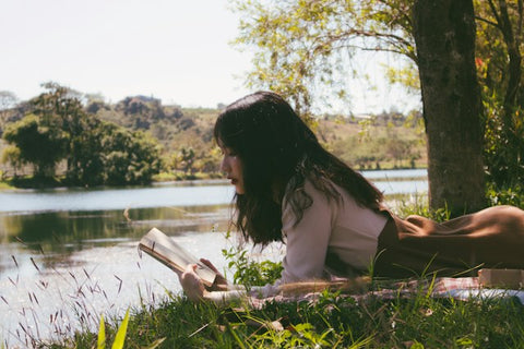 Woman Reading A Book On Grass