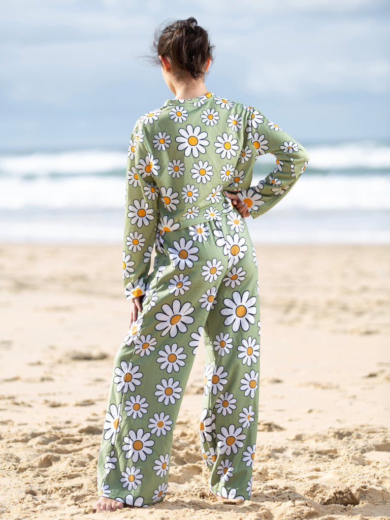Girl wearing flare pants at the beach with a sage green daisy print | Raiana's Vibes