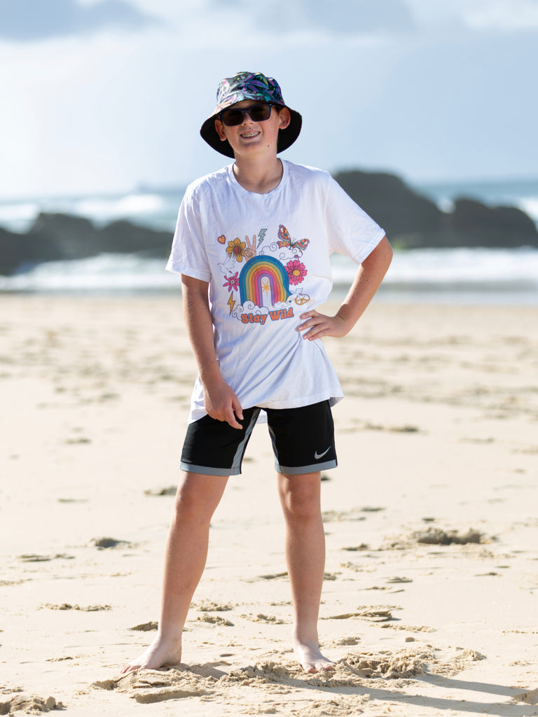Boy at the beach wearing a white tshirt wit "Stay Wild" written on the front | Raiana's Vibes