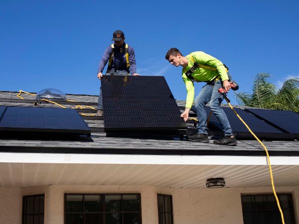 2 male workers installing solar panels for the property roof.png