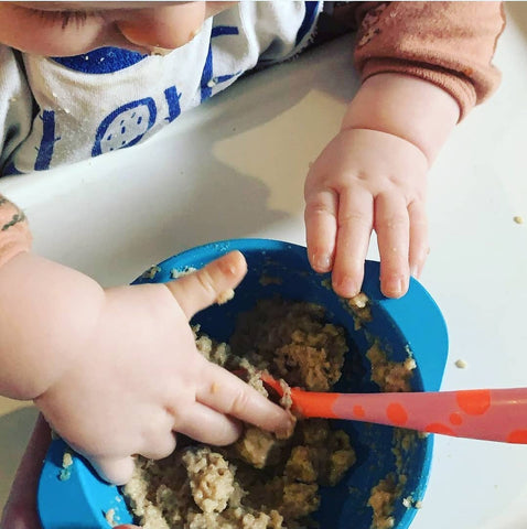 infant eating out of a blue bobo&boo snack bowl