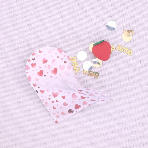 opened paper heart pocket containing confetti and a strawberry eraser
