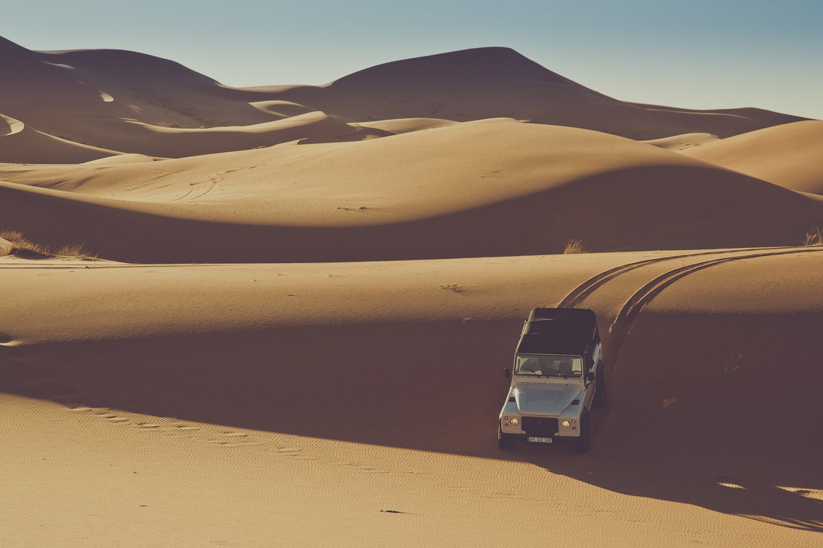 A Land Rover driving across sand dunes in a dessert in Morocco 