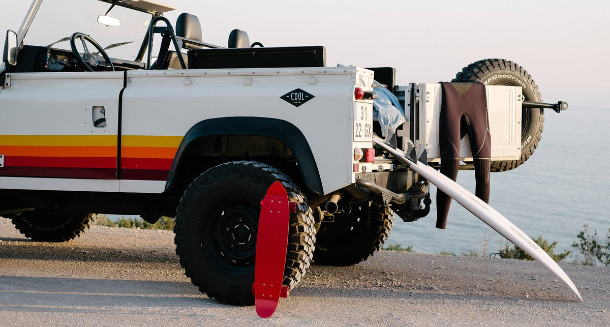 A Land Rover Defender with a surfboard and kit