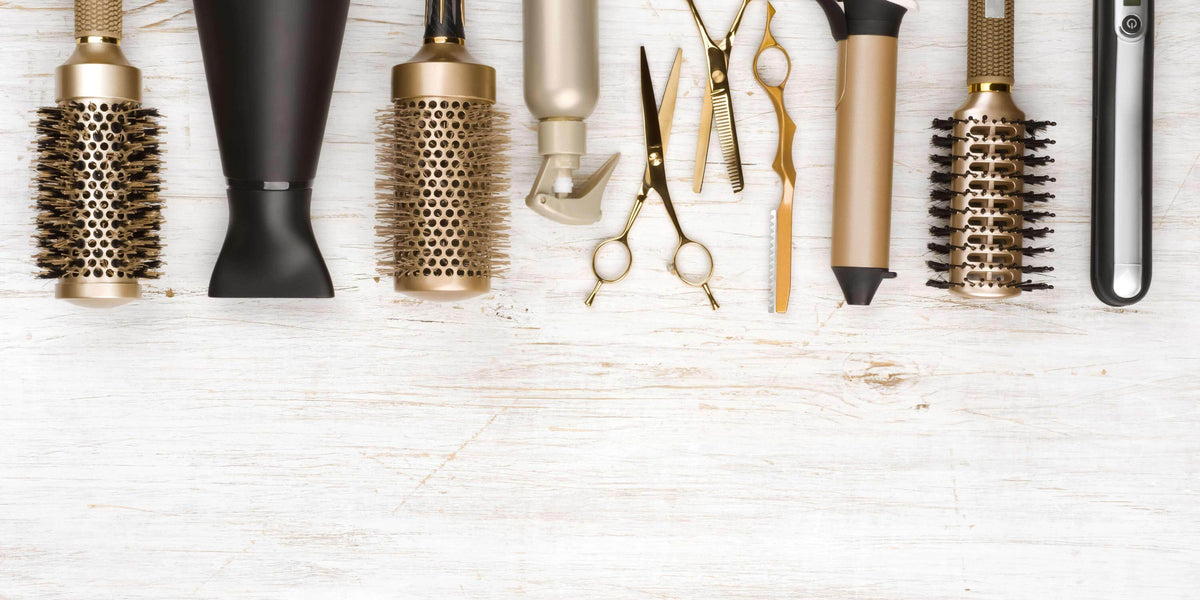 Golden hair salon tools: hair brush, blow dryer, golden scissors, curling iron