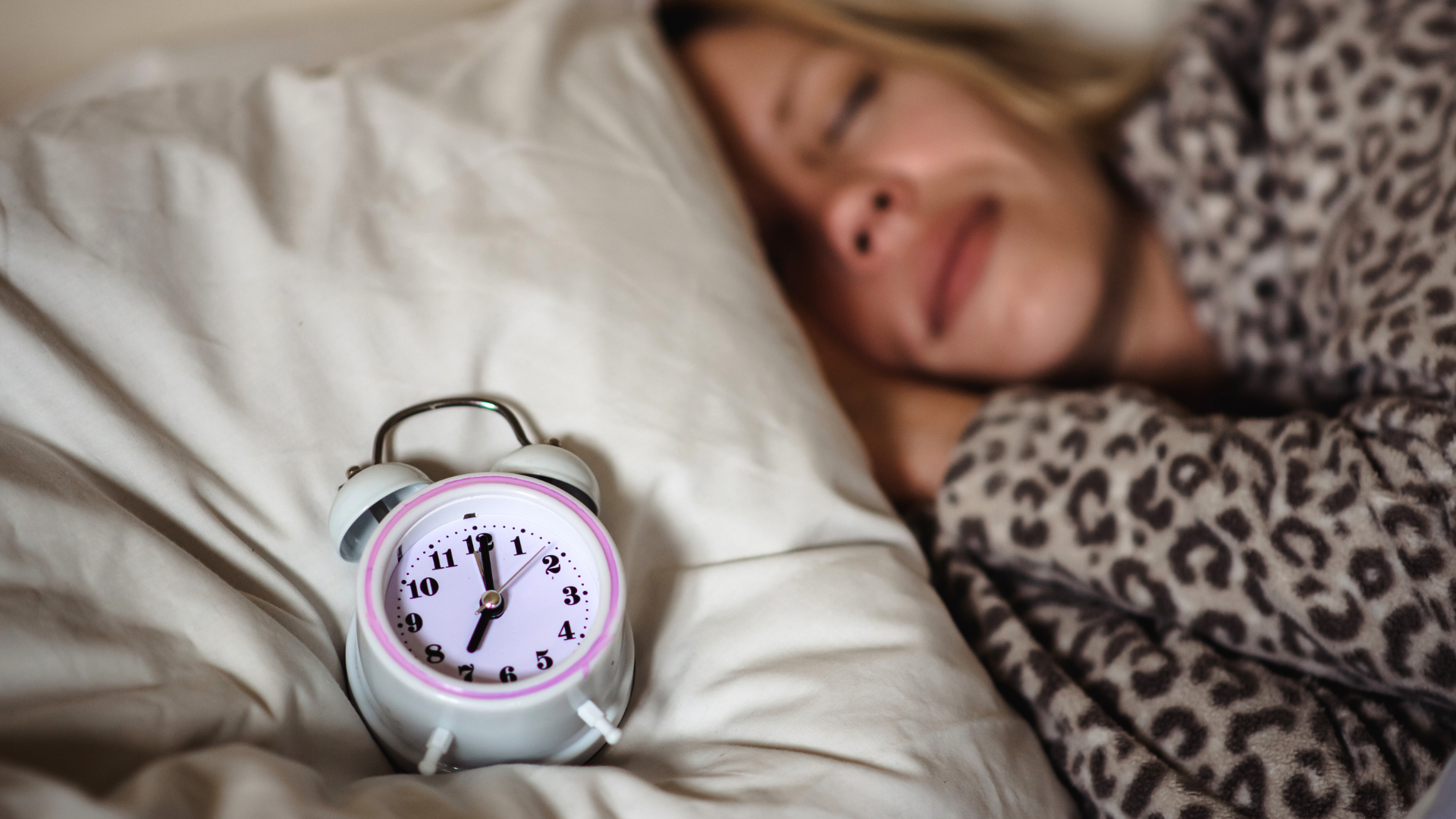 woman sleeping in her bed next to an alarm clock