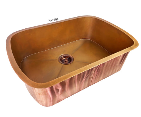 Custom radius corner pure copper sink with a centered drain and weathered patina finish.