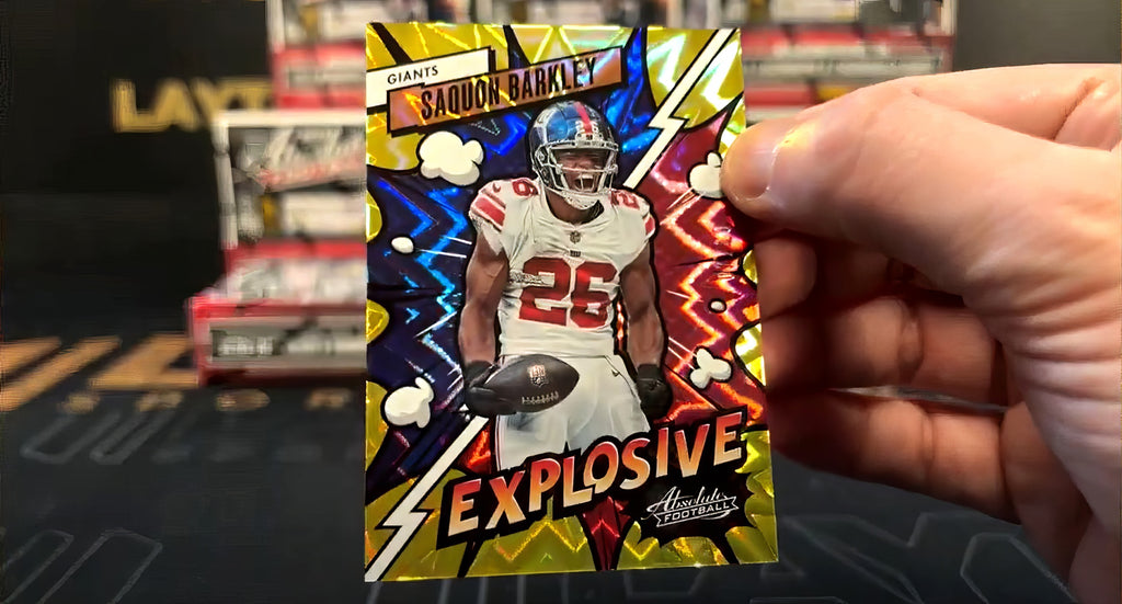 A point-of-view image of someone holding a 2023 Panini Absolute Explosive Gold football card
