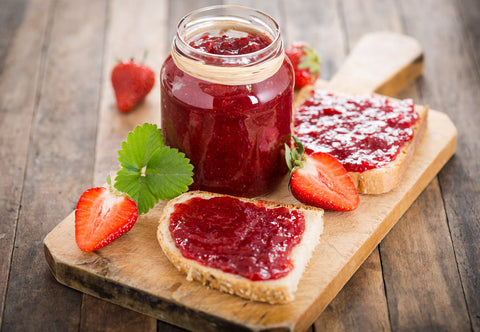 Jar or jam next to slices of toast with jam.