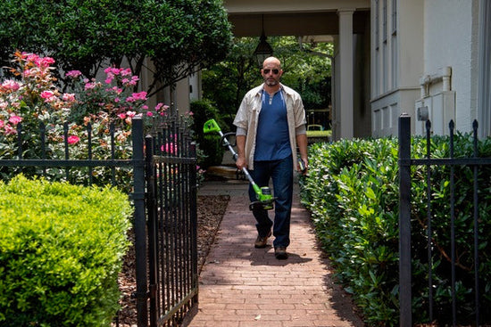 Man walking on brick path with Greenworks trimmer