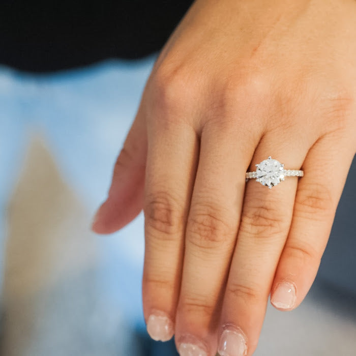 Silver diamond engagement ring on a finger
