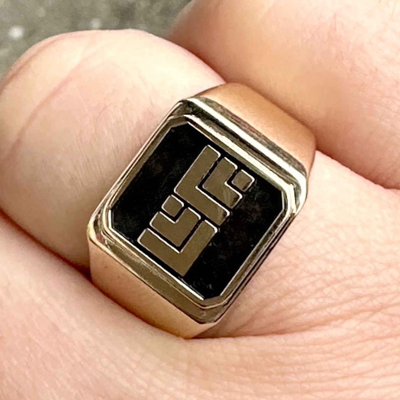 Close-up of a gold ring with a black stone on a finger