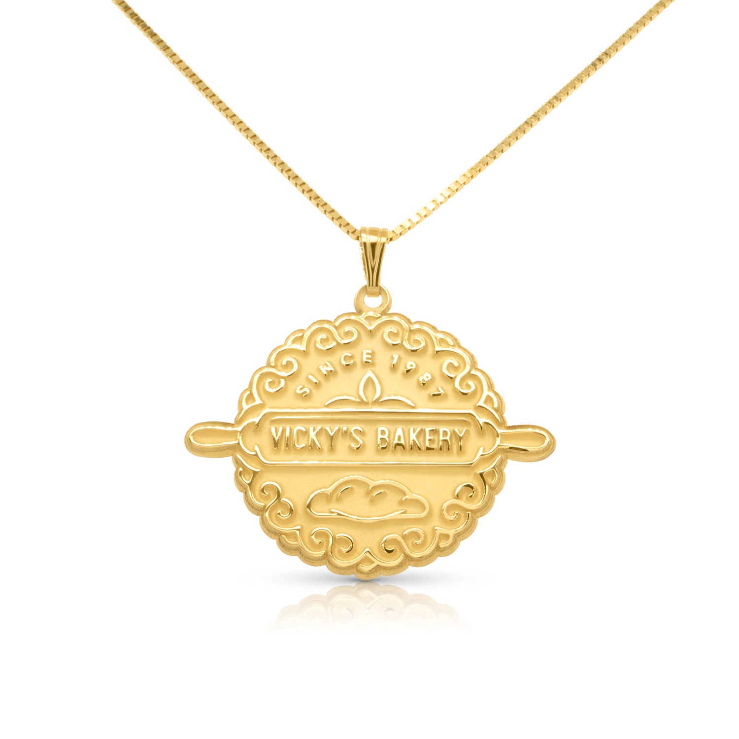 Gold round pendant with an engraved store name on a white background
