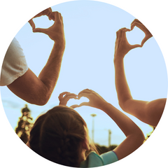 A family making a hand heart gesture up to a sunny sky