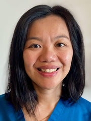 A headshot of acupuncturist Ka Hang Leoungk smiling and wearing blue scrubs