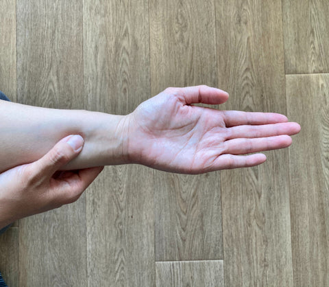 A forearm with the hand face up. Pressure is applied with the opposite thumb to a stress-relieving point 3 fingers distance from the wrist crease