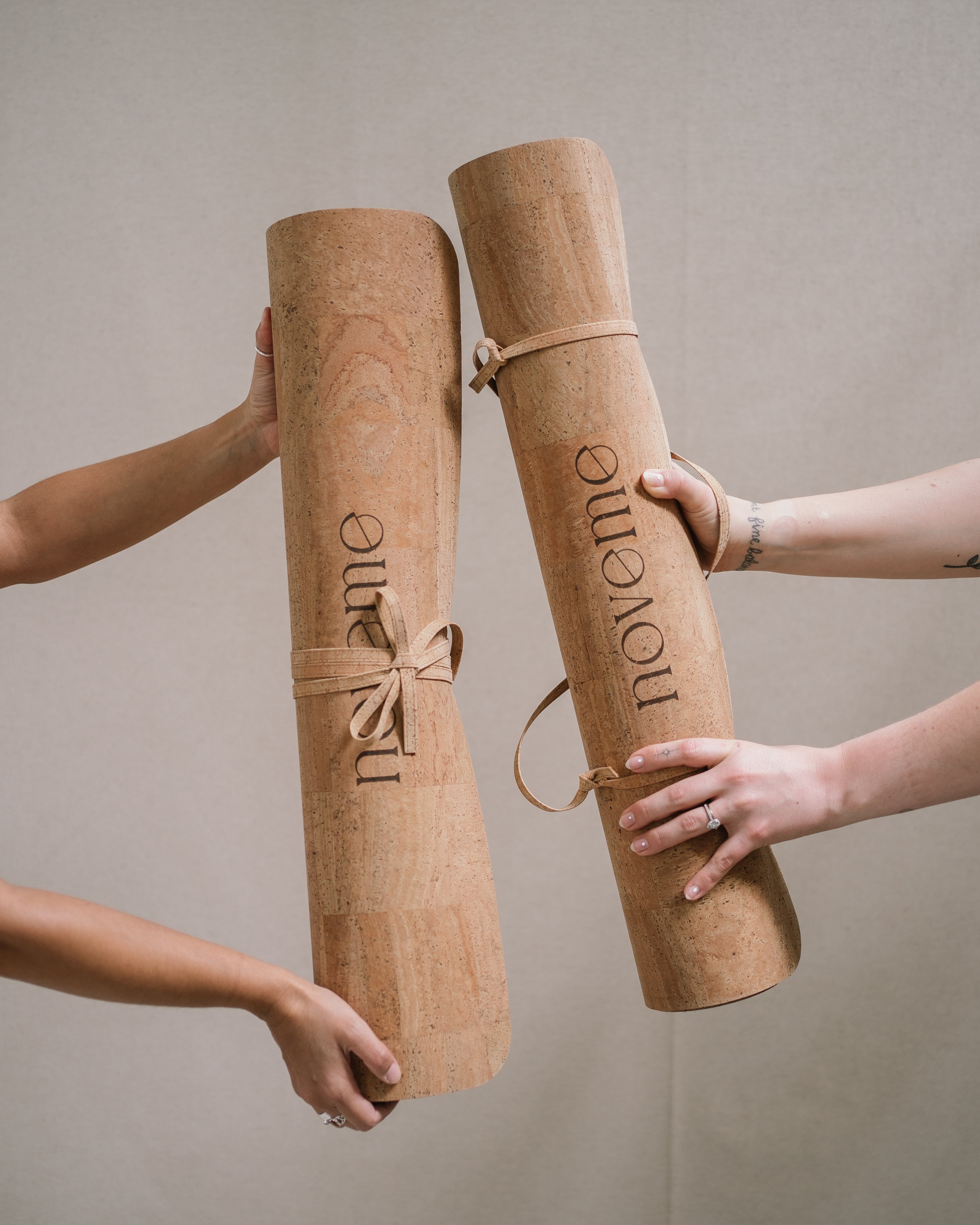 two models holding a noveme cork yoga mat each