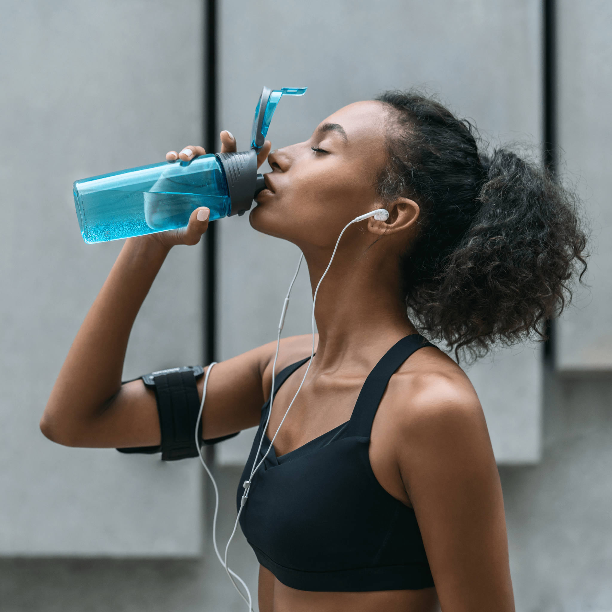 A woman drinking from a water bottle | Ultimate Nutrition