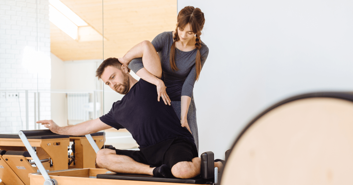 Pilates instructor positing student | Ultimate Nutrition