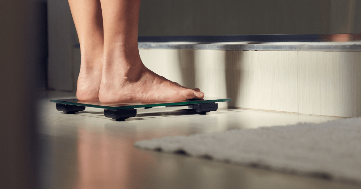 A person standing on a scale | Ultimate Nutrition