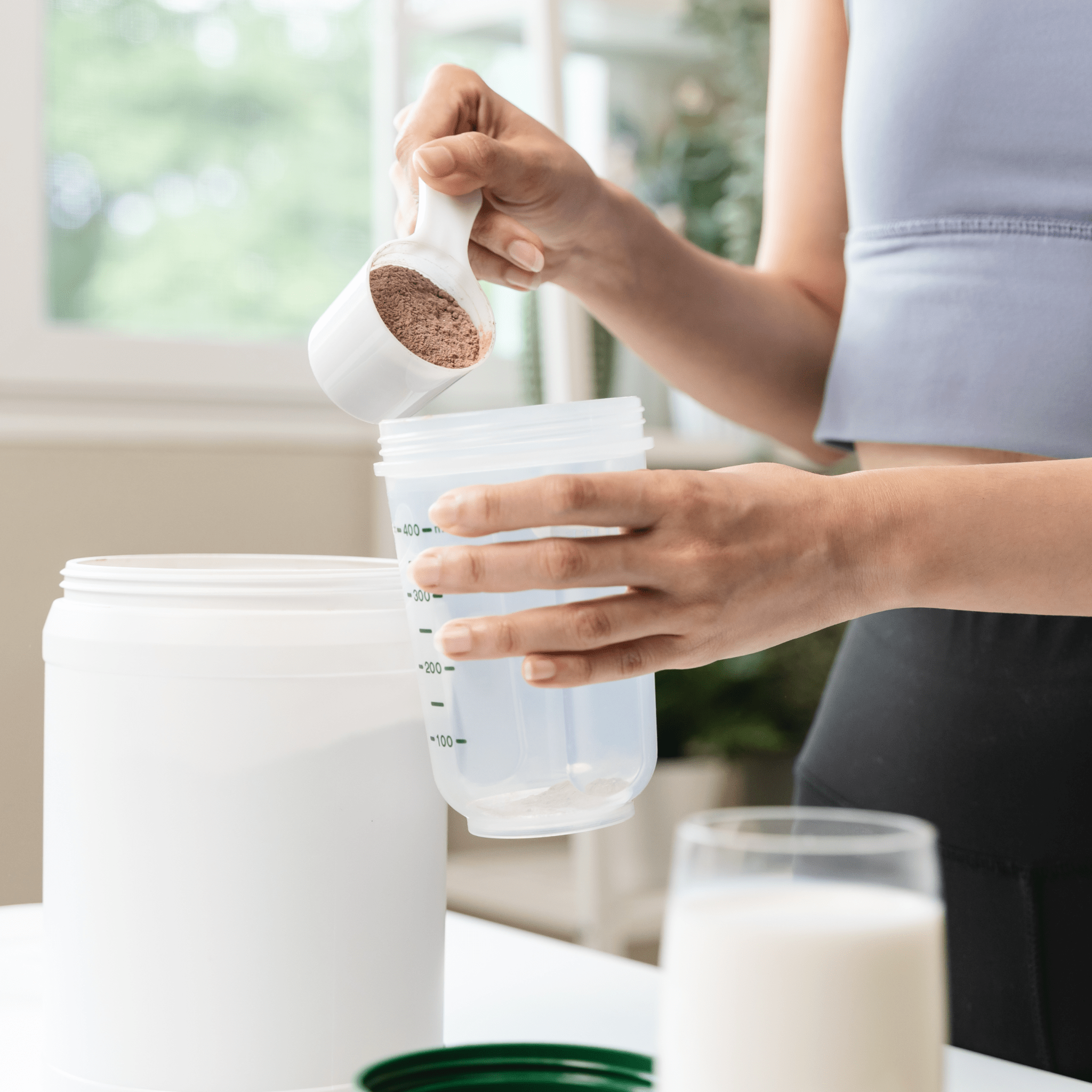 En kvinna lägger till protein i en shaker | Ultimate Nutrition