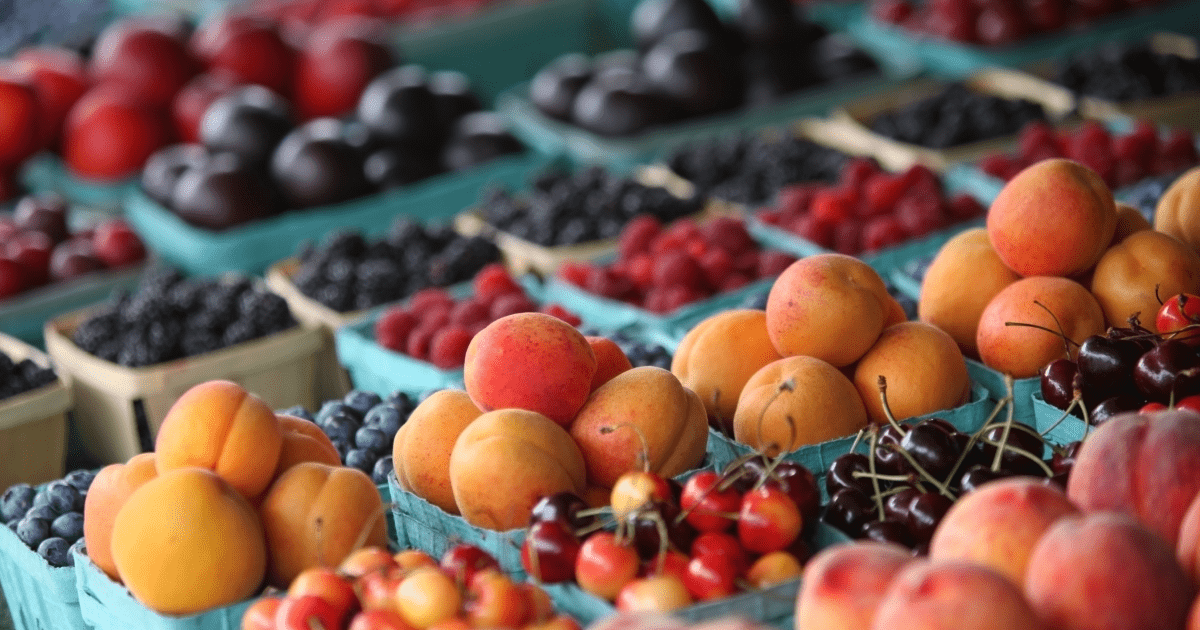Peaches, grapes, and cherries at a market | Ultimate Nutrition