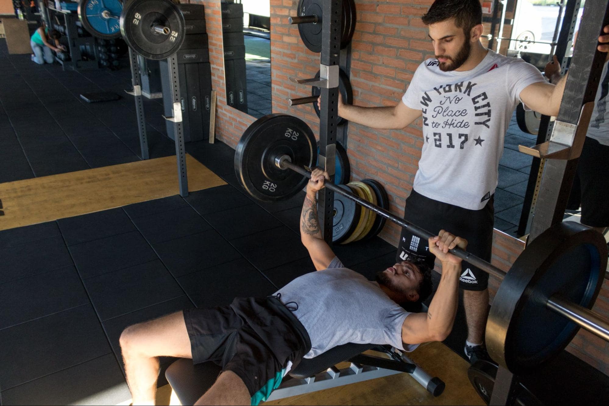 Person bench pressing with a spotter