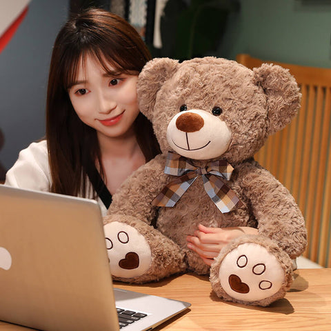 Mädchen mit dem hellbraunen Teddybär vor dem Laptop