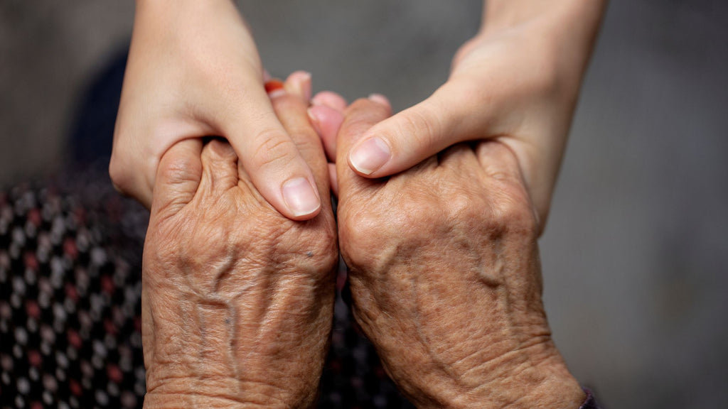 Older person and younger person hold hands