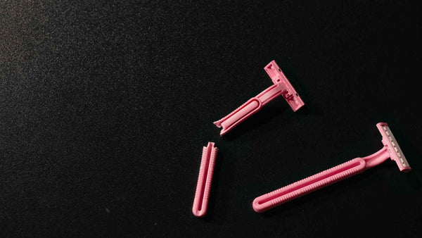 Two pink razors on a black surface.