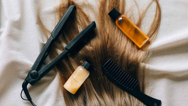Hair tools, including a bottle of shampoo and a bottle of conditioner laying on top of a bed.